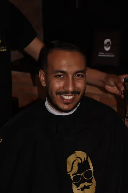 Portrait souriant en barbershop, ambiance chaleureuse.